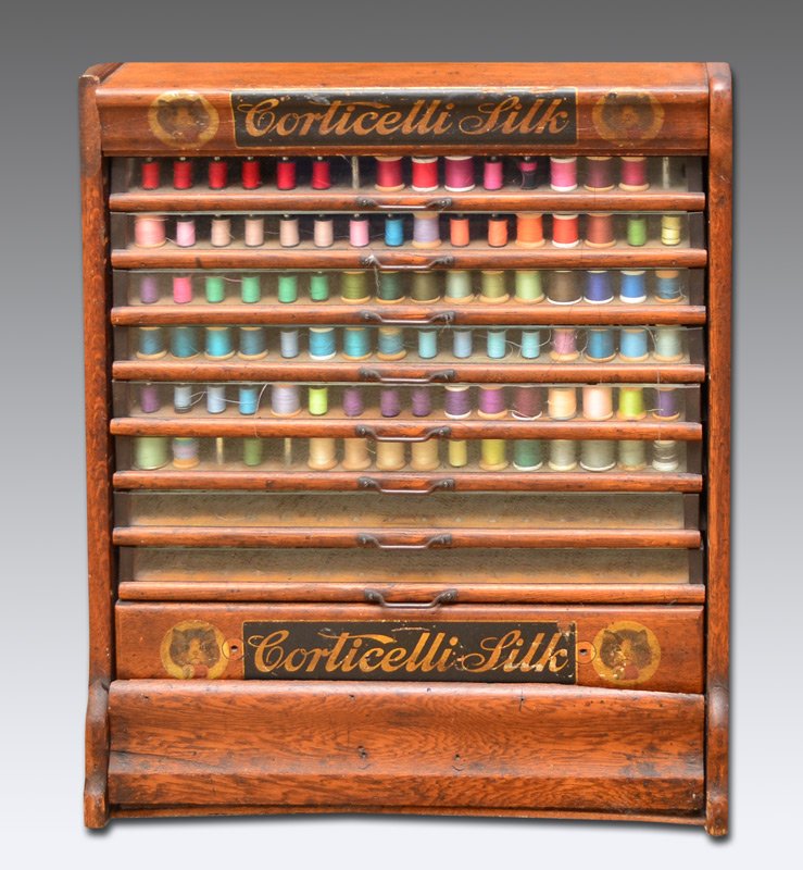 CORTICELLI GLASS FRONT OAK SPOOL CABINET: CORTICELLI GLASS FRONT OAK SPOOL CABINET: Advertising ''Corticelli Spool Silk'', oak case with original decals. 8 glass front drawers over 2 lower drawer. Overall 25 1/2'' h. x 21 1/2'' x 19''.