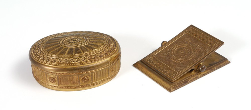 2 TIFFANY ADAMS BRONZE DESK ACCESSORIES: 2 TIFFANY ADAMS BRONZE DESK ACCESSORIES: 2 gilt bronze pieces total in the "Adams" pattern by Tiffany Studios to include 1) Oval box with hinged lid #1782, 1 1/2" h. x 4 1/4" x 3 3/8". 2) Desk clip #1