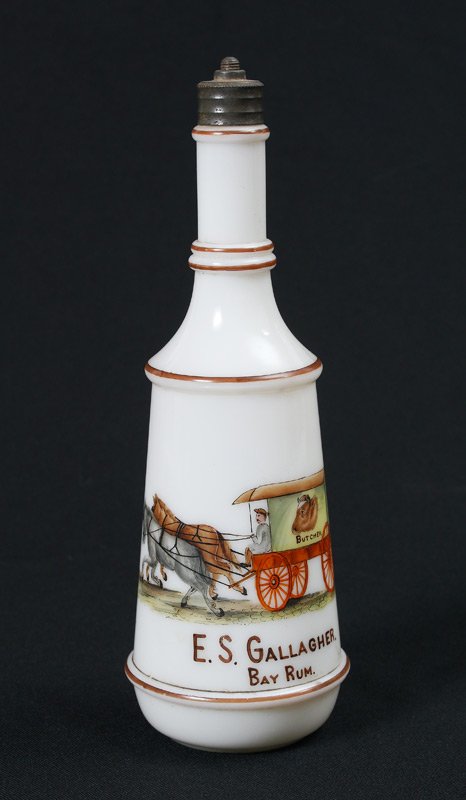 OCCUPATIONAL MILK GLASS BARBER BOTTLE: BUTCHER OCCUPATIONAL MILK GLASS BAY RUM BARBER BOTTLE: Hand painted decoration of a butcher's cart, Bay Rum. Measures approx. 10". From the William Merner Collection.