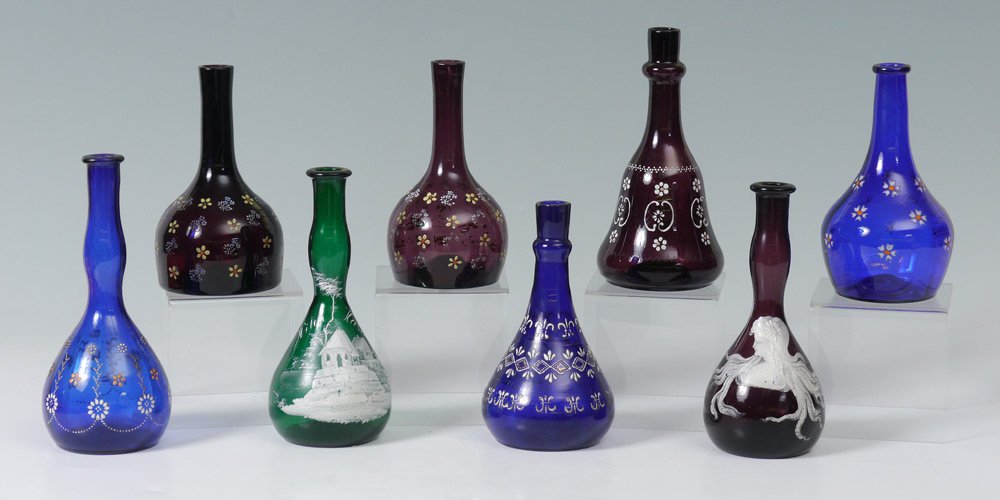 8 ENAMELED BARBER BOTTLES: 8 ENAMELED GLASS BARBER BOTTLES: Cobalt blue, purple and green glass with enameled decoration including Art Nouveau maiden and Witch Hazel. Measures 7-8" tall. From the William Merner Collection.
