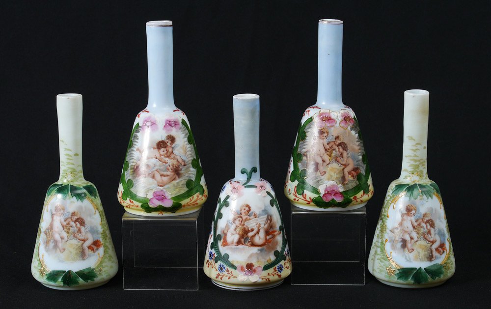5 MILK GLASS CHERUBIC BARBER BOTTLES: A GROUP OF 5 BELL SHAPED MILK GLASS BARBER BOTTLES: Each with a transfer design of cherubs at play. Measures approx. 8" tall. From the William Merner Collection.