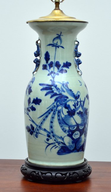 CHINESE BLUE DECORATED CELADON LAMP: CHINESE BLUE DECORATED CELADON LAMP: Floral blue decorated earthenware body, unmarked on base. Carved wood base, single socket fixture. Overall measures 35 3/4" h. x 8 1/2", sold with cloth shade 18 1
