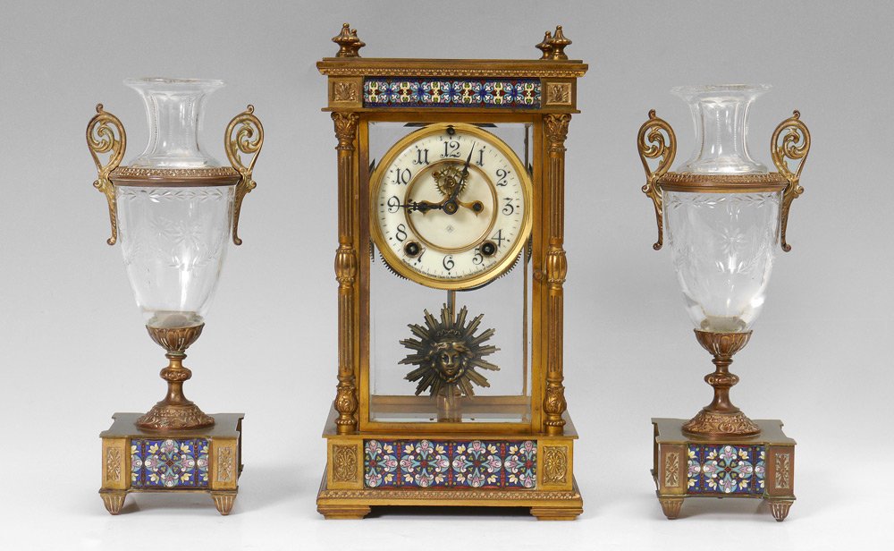 ANSONIA CHAMPLEVE CLOCK GARNITURE SET: ANSONIA CHAMPLEVE CLOCK GARNITURE SET: 3 piece total to include a brass case crystal regulator clock by the Ansonia Clock Co., New York. Case with beveled glass sides, column corners, champleve enamel