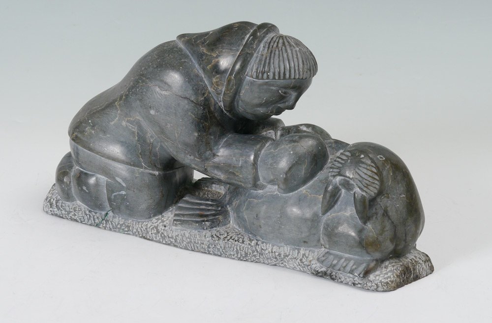 INUIT STONE CARVING OF MAN SKINNING A WALRUS: INUIT STONE CARVING OF MAN SKINNING A WALRUS: Base with etched initials CDC, 1760, and partial Canadian Eskimo Art sticker. No visible signature. Measures 8" h. x 14 1/2" x 5".