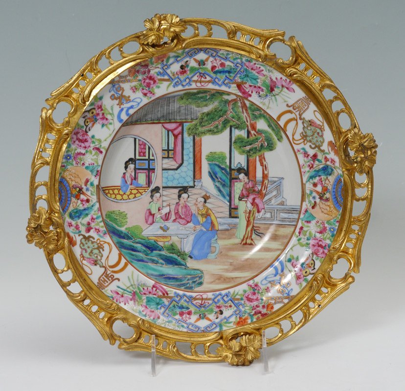 ORMOLU MOUNTED CHINESE BOWL Genre Geisha scene: ORMOLU MOUNTED CHINESE BOWL: Enamel and paint decorated shallow bowl with scene of Geisha at an outdoor table. Raised in a gilt open work frame on four feet. Unmarked. 3 1/2"h. plus leaf finials, 12 1