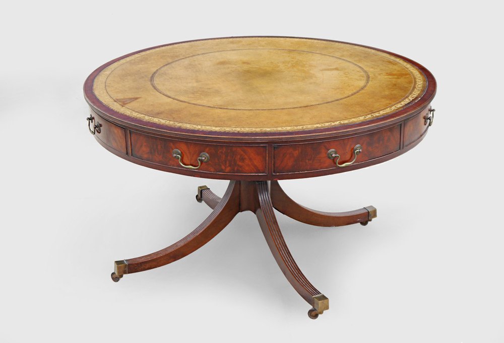 REGENCY STYLE MAHOGANY DRUM TABLE: REGENCY STYLE MAHOGANY DRUM TABLE: Round top with inset embossed leather, skirt with 4 drawers. Pedestal base with 4 splayed legs ending in brass caps with castors. 28" h. x 49 1/2" dia.