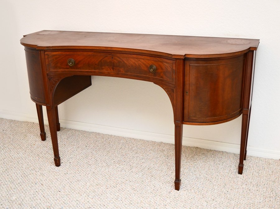 ROBERT MITCHELL MAHOGANY SIDEBOARD: ROBERT MITCHELL MAHOGANY SIDEBOARD: Shaped top, single center drawer, rounded side doors open to single shelf. Carved corner decorations under drawer, tapered legs, paper tag on back, overall 38 1/4" 