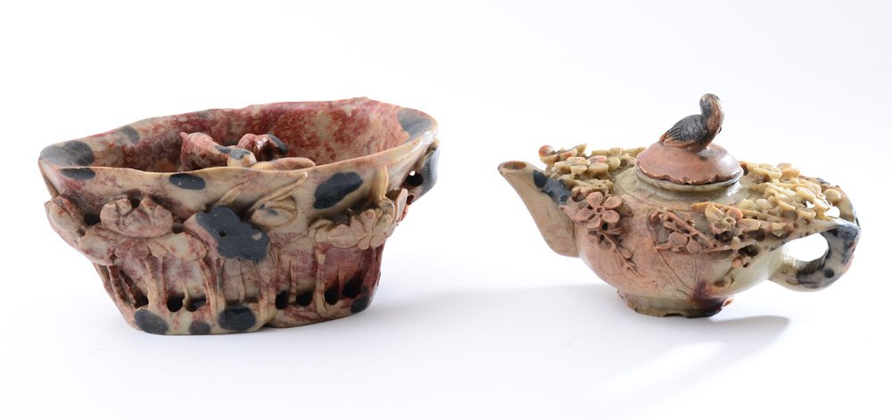 2 CARVED SOAPSTONE VESSELS: 2 CARVED SOAPSTONE VESSELS: 2 pieces total to include 1) Teapot with floral decoration, lid with bird finial, signed on base. 3 3/4'' h. x 6 1/4'' x 4 1/4''. 2) Libation cup with carved figures interi