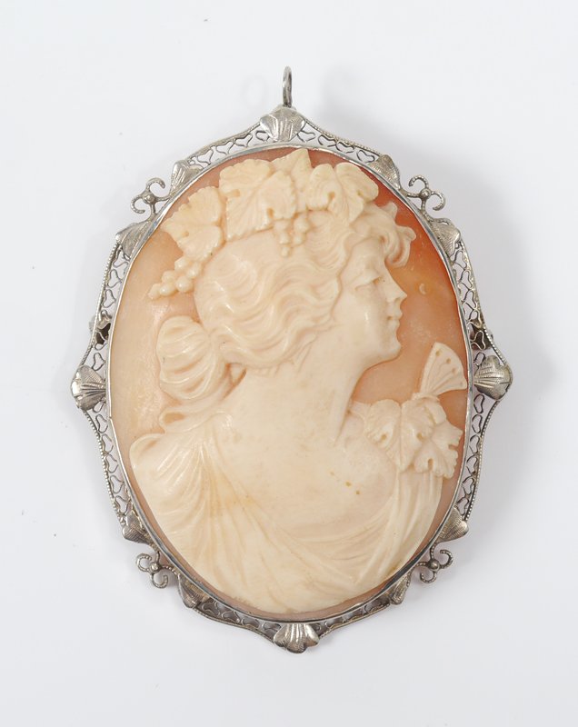 14K GOLD FRAMED CAMEO BROOCH PENDANT: LARGE 14K WHITE GOLD FRAMED CAMEO PENDANT / BROOCH: Shell carved depiction of a wavy haired beauty with grapes and leaves in her hair and butterfly on her shoulder. Filigree frame. 2 1/8" x 1 3/4".