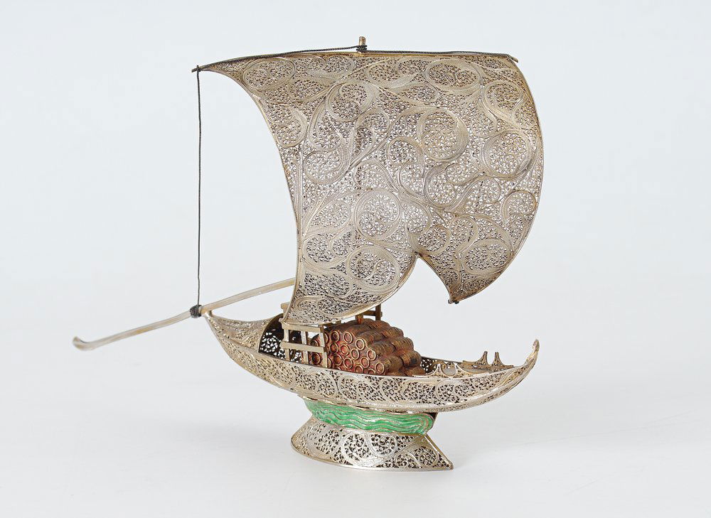 STERLING MODEL OF A BOAT: STERLING MODEL OF A BOAT: Pierced and engraved decorated all over, figure of a single sail boat with a load of wine barrels as cargo. Green enameled waves, partial sterling mark on rudder. Overall mea