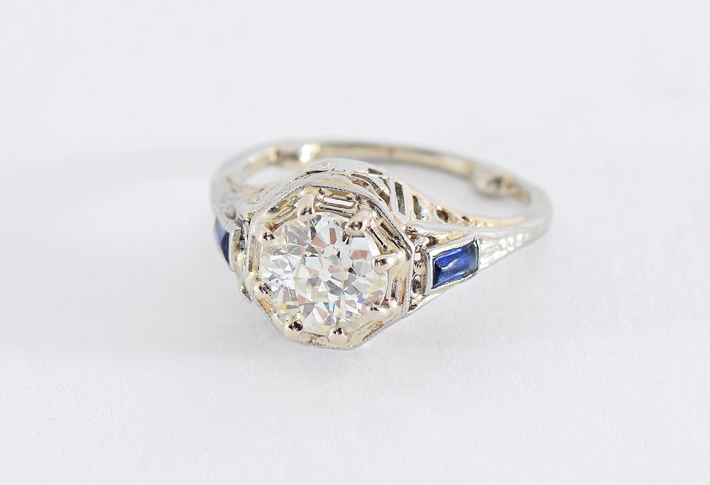 DECO .90 CT DIAMOND SOLITAIRE FILIGREE RING SZ 2: ART DECO .90 CT DIAMOND SOLITAIRE RING: 18K white gold filigree mounting centering an old European round cut diamond flanked by 2 baguette synthetic sapphires. The diamond is rated VS2 clarity and I c