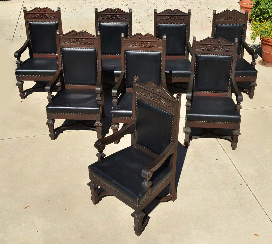 SET OF 8 CARVED SPANISH REVIVAL STYLE ARM CHAIRS: SET OF 8 CARVED SPANISH REVIVAL STYLE ARM CHAIRS: Carved and shaped top rail with applied decoration, arms with scroll hand holds, carved and tapered front legs, shaped supports. Tacked black leather