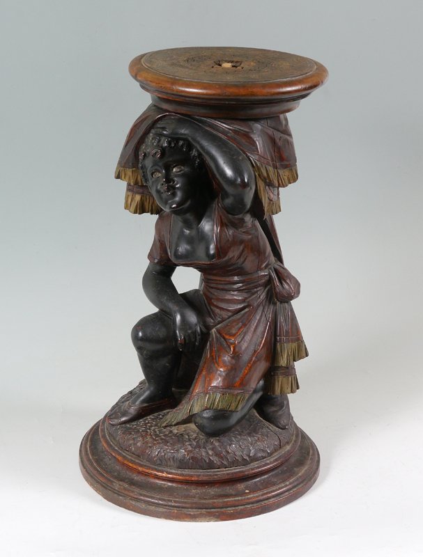 LARGE CARVED FIGURAL PEDESTAL PLANT STAND: LARGE CARVED FIGURAL PEDESTAL PLANT STAND: Ebonized carved wood figure of a maiden on one knee with flowing garments. Removable top, overall measures 22" h. x 14" dia.