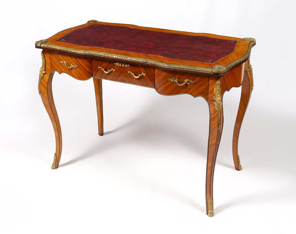 ORMOLU MOUNTED FRENCH WRITING DESK: ORMOLU MOUNTED FRENCH WRITING DESK: Shaped top, inset leather writing surface with gilt border. Ormolu mounted trim and mounts over 3 drawers, shaped legs. Overall measures 32 1/2" h. x 23 3/4" x 44 3