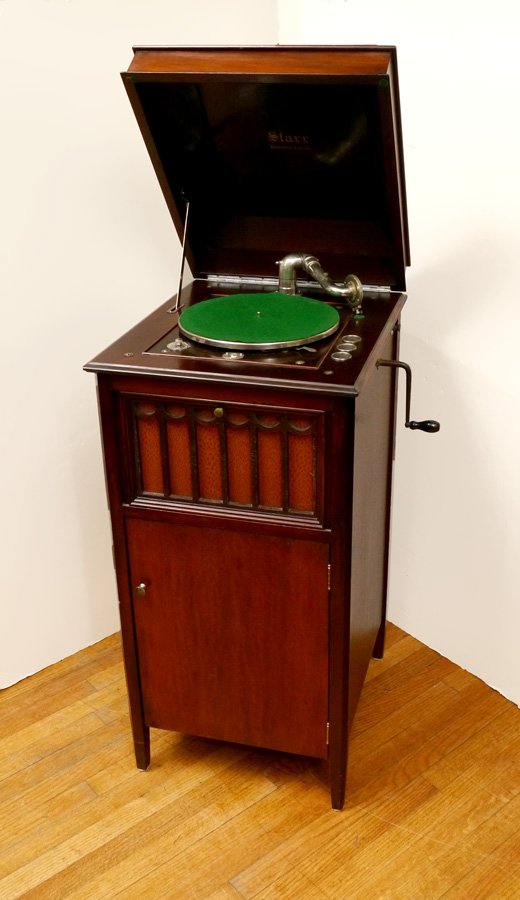 STARR MAHOGANY CASE UPRIGHT RECORD PLAYER: STARR MAHOGANY CASE UPRIGHT RECORD PLAYER: Internal horn behind fretwork door with cloth cover over single door with record storage. Overall measures 42 1/2" h. x 19" x 22". Sold with an assortment of