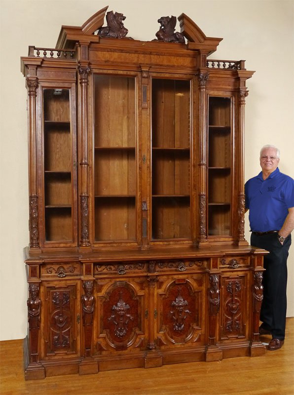 HORNER ERA FIGURAL CARVED BOOKCASE CABINET: MONUMENTAL HORNER ERA FIGURAL CARVED BOOKCASE CABINET: Broken arch pediment with figural winged griffins, stick and ball gallery. 4 glass doors with carved and fluted full column supports. Base with 4