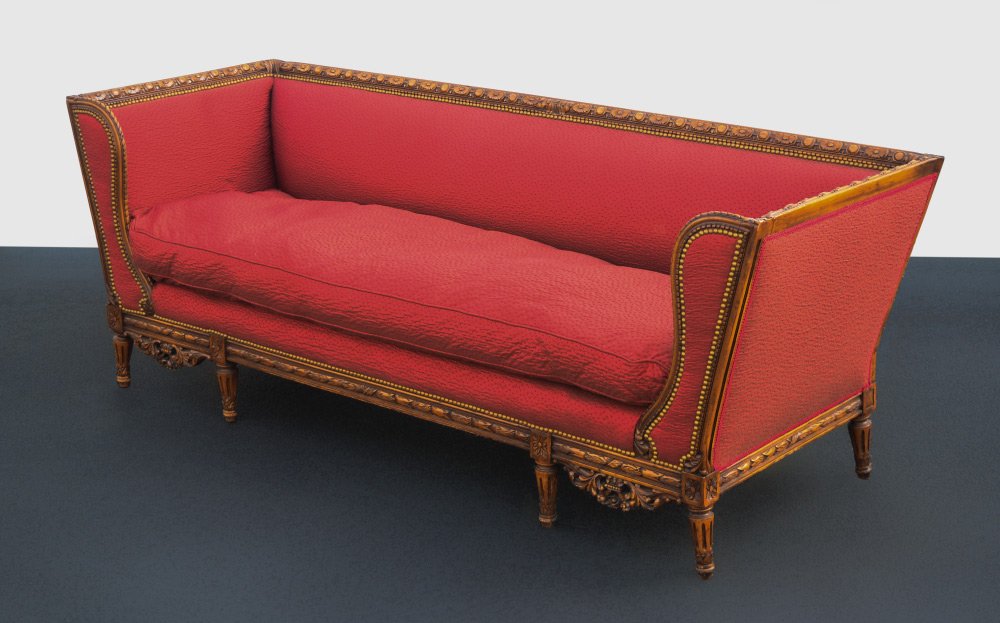 FRENCH STYLE CARVED SOFA: FRENCH STYLE CARVED SOFA: Carved top rail, shaped wing front, carved skirt and legs. Tacked red upholstery, overall measures 30 1/2" h. x 85" x 30".