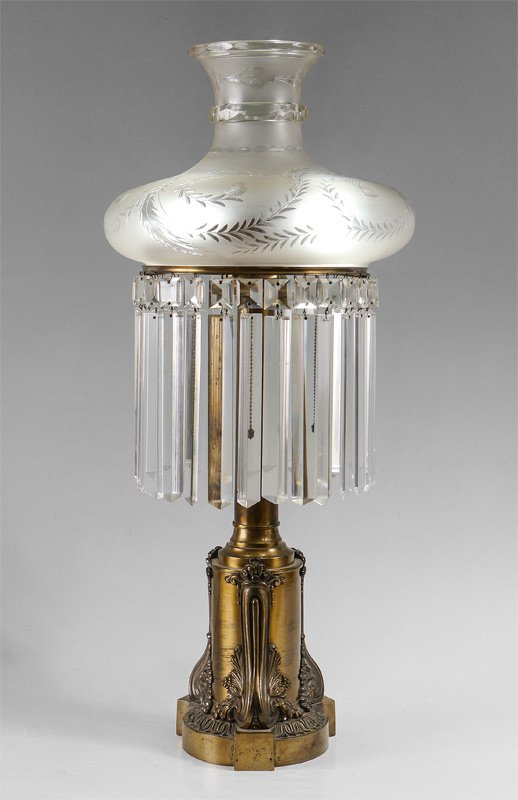 GILT BRASS AND CRYSTAL SINUMBRA LAMP: GILT BRASS AND CRYSTAL SINUMBRA LAMP: Electrified, gilt brass base with applied decoration, large hanging crystal prims. Etched glass shade, overall measures 30" h. x 14" assembled, base alone 23 x 10