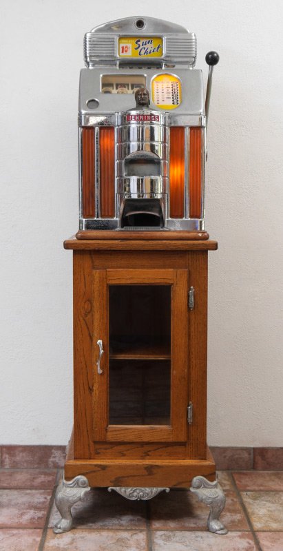 JENNINGS SUN CHIEF 10 CENT SLOT MACHINE: JENNINGS SUN CHIEF 10 CENT SLOT MACHINE: Chrome top with yellow background Sun Chief inserts, 3 reels, amber catalin illuminated front panels, original Jennings labels either side of oak case. Measure