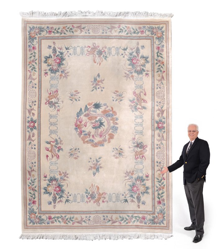 25 YR OLD CHINESE H K WOOL RUG 8'10" x 12': APPROX. 20-30 YR. OLD CHINESE HAND KNOTTED WOOL RUG, 8'10" x 12'1": The ivory field of this rug has a round central medallion with a dragon coiled around flowers and leaves. The pastel colors of the d
