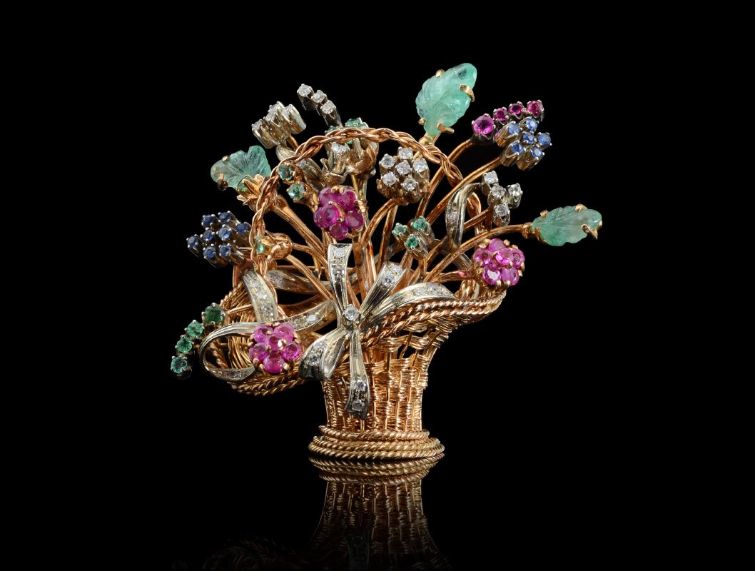 EN TREMBLANT DIAMOND & GEMSTONE BASKET BROOCH: EN TREMBLANT 18K GEMSTONE BASKET BROOCH: A beautiful handmade 18K yellow gold sculptural woven basket with a ribbon of diamonds wrapped around a bouquet of 53 rubies, sapphires and emeralds, and 3 car