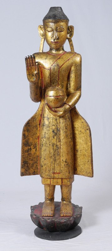 LARGE GILDED CARVED WOOD STANDING BODHISATTVA: LARGE GILDED CARVED WOOD STANDING BODHISATTVA: Standing Buddhist figure with one hand outstretched, the other holding a box, standing on lotus plinth. Overall measures 61 1/2" h. x 18 1/2" x 28".