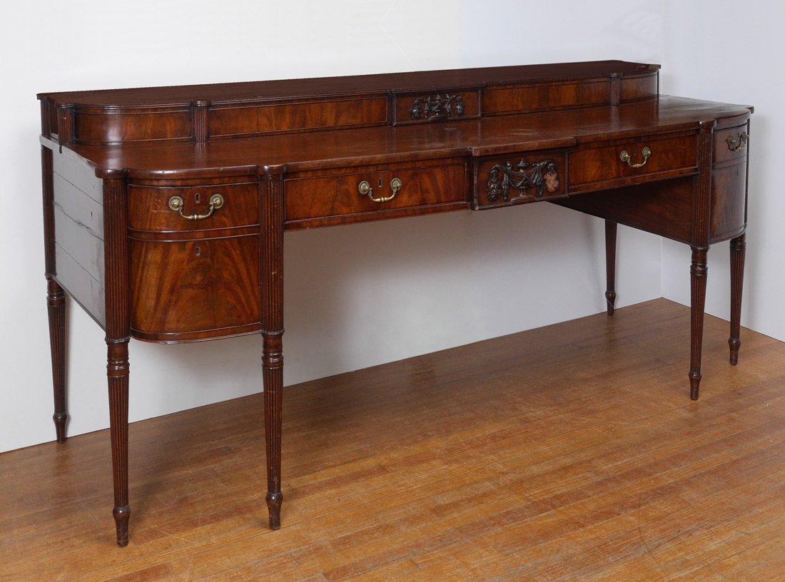 19TH CENTURY SHERATON SIDEBOARD: 19TH CENTURY SHERATON SIDEBOARD: Stepped top with applied carved urn decoration in center, reeded 3/4 columns under cookie corners. Base with center urn decoration, single drawer either side, left sid