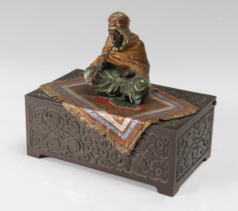 BERGMAN BRONZE ORIENTALIST BOX: BERGMAN AUSTRIAN BRONZE ORIENTALIST BOX: Franz Xavier Bergman (1861-1936). Hinged box surmounted by a man with pipe, sitting on a colorful rug. Note the detail of the rug overlapping the box. Wood lin