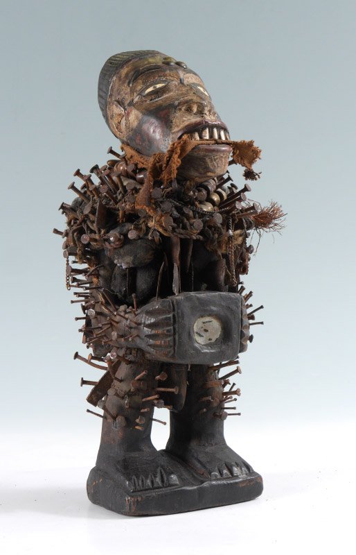 AFRICAN CARVED BAKONGO NAIL FETISH FIGURINE: AFRICAN CARVED BAKONGO NAIL FETISH FIGURINE: Carved wood paint decorated figure with nails, beads, mirror and brads. Bakongo tribe, Congo. 14" h. x 7" x 5 1/2".