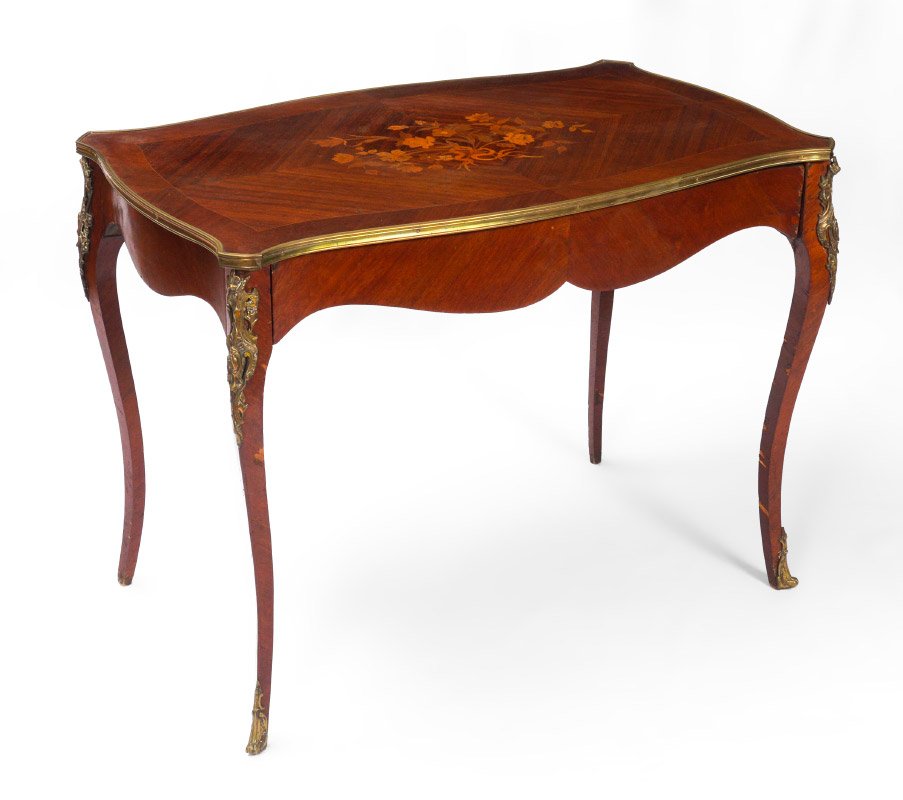 FRENCH ORMOLU MOUNTED WRITING TABLE: FRENCH ORMOLU MOUNTED WRITING TABLE: Bookmatch veneer with floral inlay top, brass trim, ormolu mounts at top of shaped legs and at feet. Shaped skirt with single drawer, 29 1/2" h. x 38 3/4" x 22 3/4