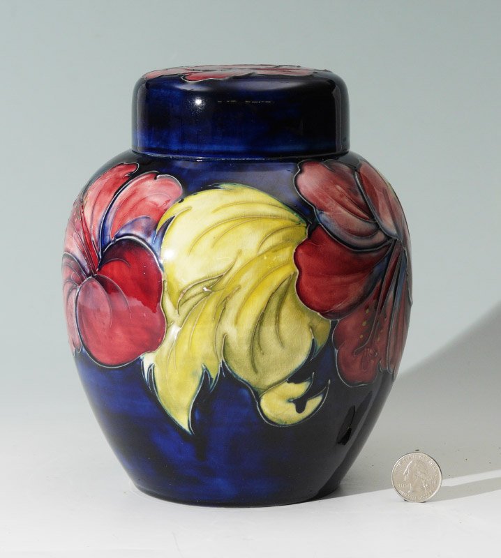 MOORCROFT HIBISCUS COVERED GINGER JAR: MOORCROFT HIBISCUS COVERED GINGER JAR: Blue ground, decorated with polychrome hibiscus flowers, impressed Moorcroft marks and original stickers. Overall measures 8'' h. x 6 1/4''.