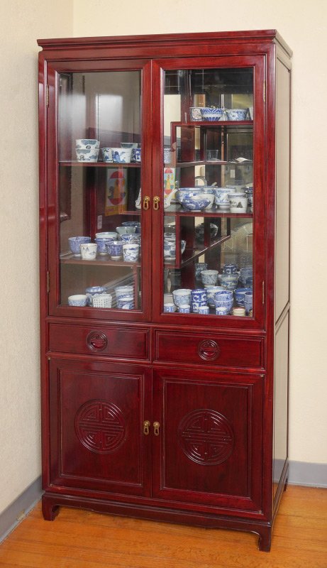 ORIENTAL MOTIF CURIO DISPLAY CABINET: ORIENTAL MOTIF CURIO DISPLAY CABINET: 2 glass doors, interior with mirrored back and multi level shelves. 2 half drawers over 2 doors with carved panels, on 4 legs. 76" h. x 35 3/4" x 15 3/4".