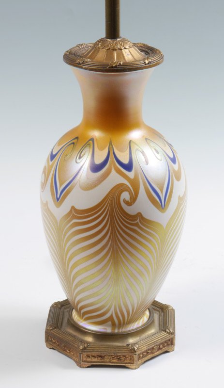 QUEZAL IRIDESCENT PULLED FEATHER TABLE LAMP: QUEZAL IRIDESCENT PULLED FEATHER TABLE LAMP: Attributed Quezal iridescent art glass body with pulled feather design ending in swirls. Gilt metal base marked M. S. Co., single socket fixture. Overall m