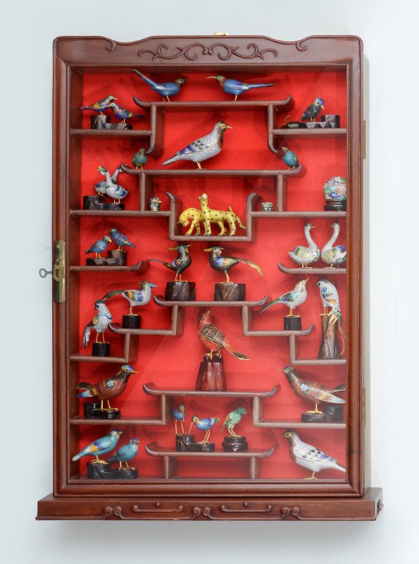 HANGING ORIENTAL WALL CABINET WITH CLOISONNE ANIMALS: HANGING ORIENTAL WALL CABINET WITH CLOISONNE ANIMALS: The carved oriental motif hanging display cabinet and contents, approx. 36 cloisonne animals, mostly birds, the largest being a cardinal on wood s