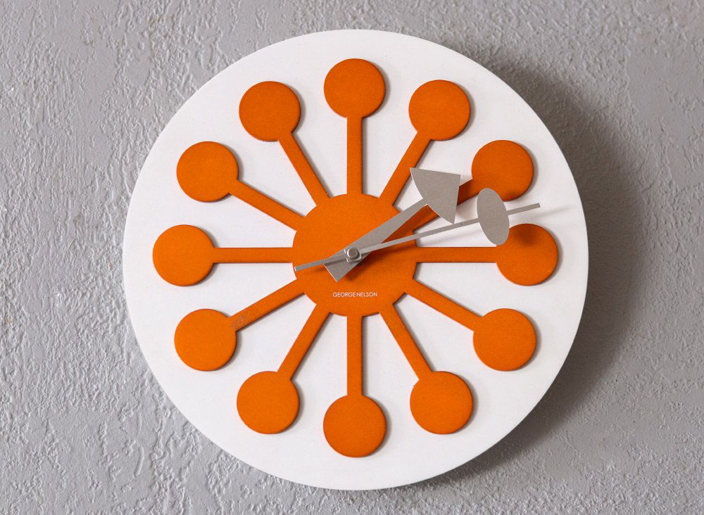 SIGNED GEORGE NELSON WALL CLOCK: SIGNED GEORGE NELSON WALL CLOCK: White painted wood back with orange ''lollipop'' design, marked George Nelson on dial, battery quartz movement. 12'' dia.