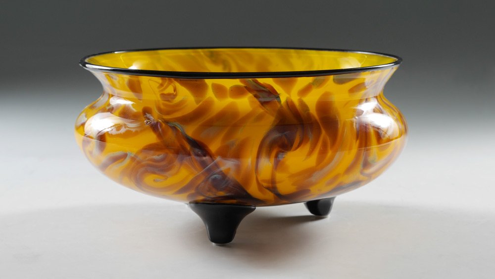 LOETZ ART GLASS FOOTED CENTERBOWL: LOETZ ART GLASS FOOTED CENTERBOWL: Unmarked attribution to Loetz, yellow interior, marble exterior with brown and iridescent swirls, black rim and 3 black feet. Overall measures 4 3/4" h. x 9 1/2".