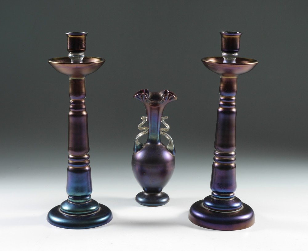 PAIR LOETZ ART GLASS CANDLESTICKS & VASE: PAIR LOETZ ART GLASS CANDLESTICKS & VASE: 3 pieces total, unmarked attributions to Loetz, to include 1-2) Pair iridescent purple glass candlesticks, 13" h. x 4 5/8", on with remnants of Austria paper