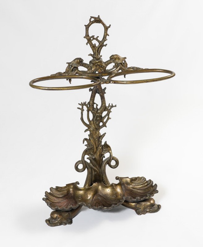 FIGURAL CAST IRON UMBRELLA STAND: FIGURAL CAST IRON UMBRELLA STAND: Patinated heavy cast iron with stylized coral body, figural dolphin feet, shell motif lower drip tray. Overall measures 31 1/2'' h. x 21 1/2'' x 9''.