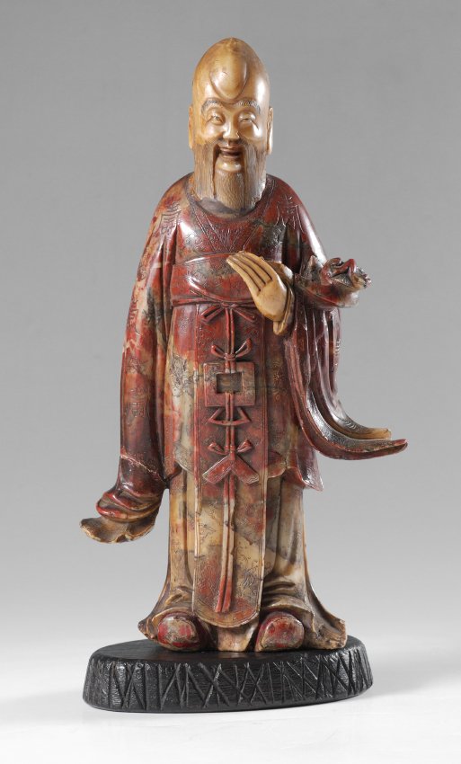 CHINESE CARVED FIGURE OF AN ELDER: CHINESE CARVED FIGURE OF AN ELDER: Nicely detailed carved soapstone figure of a scholar or elder with flowing robes, applied head and left hand, 10 3/4" h. x 6" x 2 1/2". Sold with a wood stand, 1" h.