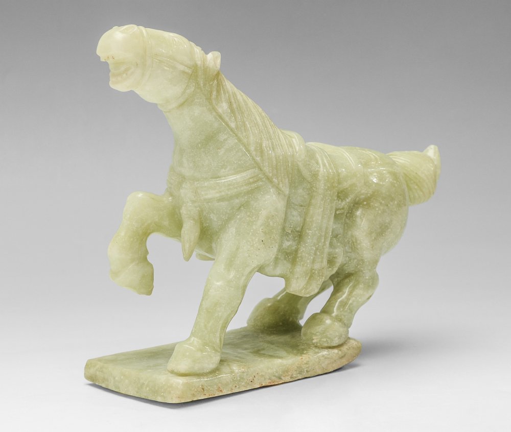 CHINESE CARVED STONE FIGURE OF A TANG HORSE: CHINESE CARVED STONE FIGURE OF A TANG HORSE: Carved green stone, age unknown, measures 8 1/4" h. x 10" x 3 1/4".