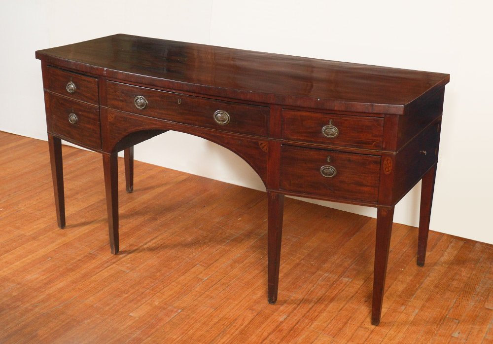 19TH CENTURY HEPPLEWHITE STYLE SIDEBOARD: 19TH CENTURY HEPPLEWHITE STYLE SIDEBOARD: Mahogany case with string inlay, bowed front, center drawer over shaped skirt, left side deep cellarette, right side 2 drawers and secret door on side. Tapere
