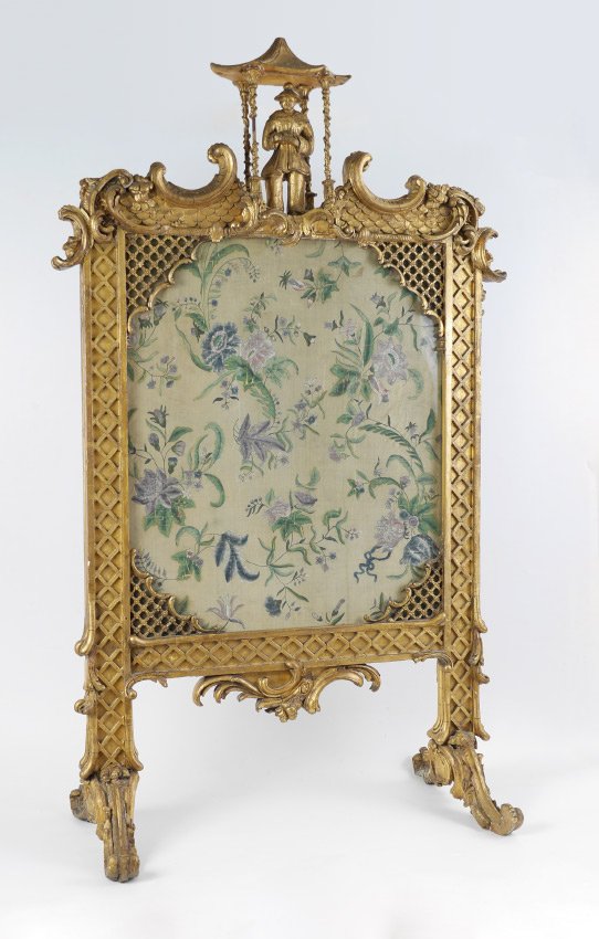 ORNATE GOLD GILT CHINESE MOTIF FIRE SCREEN: ORNATE CHINESE MOTIF FIRE SCREEN: Gold gilded wood fire screen in an oriental motif, topped by a gentlemen holding fruit standing in a temple, pierced and solid lattice work, scroll and scale designs.