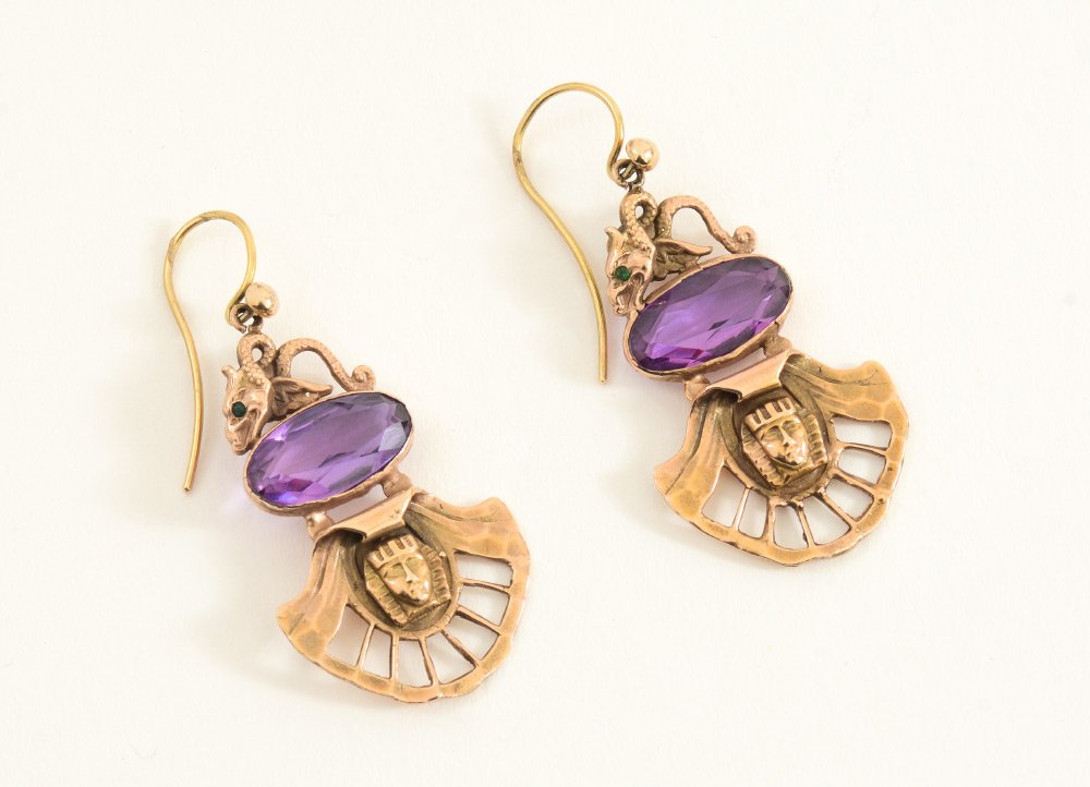 14K EGYPTIAN REVIVAL EARRINGS: 14K EGYPTIAN REVIVAL EARRINGS: 14K yellow gold Egyptian revival earrings containing two 16.00mm x 8.00mm oval shaped synthetic purple spinels. Spinels are bezel set. Two 1.00mm green stones of unknown