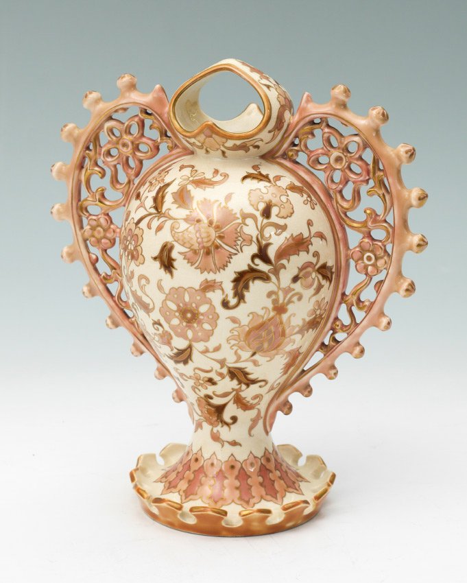 EARLY ZSONLAY PIERCED DOUBLE HANDLE VESSEL: EARLY ZSONLAY PIERCED DOUBLE HANDLE VESSEL: Covered top tim, pierced floral design double handles, body with cream ground, floral and gilt decoration, footed base with upturned ramparts. Impressed Zso
