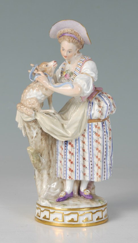 MEISSEN SHEPHERDESS AND LAMB FIGURAL GROUP: MEISSEN SHEPHERDESS AND LAMB FIGURAL GROUP: Figure of a shepherdess with lace dress tying a bow on a lamb sitting on a tree stump. Blue crossed swords mark, impressed 155 and 127, incised F68. Overall