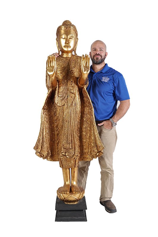 LIFE SIZE CARVED GILT WOOD BURMESE STANDING BUDDHA: LIFE SIZE CARVED GILT WOOD BURMESE STANDING BUDDHA: Carved gilt wood with mirrored glass inset accents, raised palms, closed eyes, flowing robe. Affixed to ebonized stand, overall 74 1/2" h. x 27" x 1
