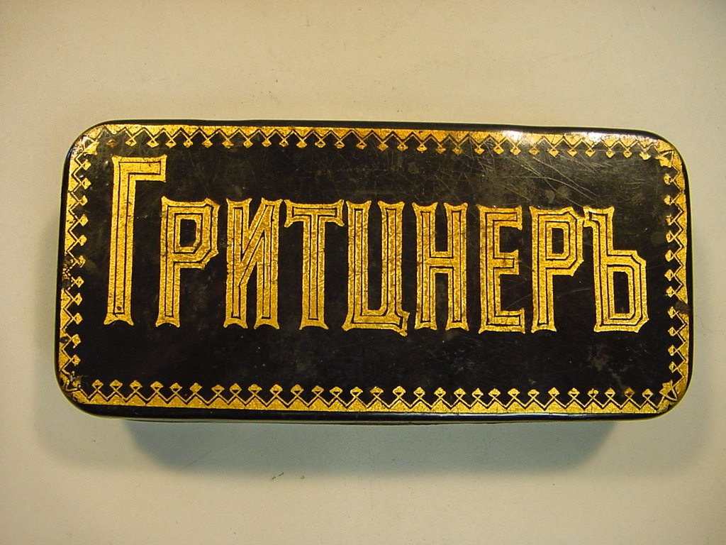 RUSSIAN Gilt Tin Box for Sewing Machine GRITZNER: Made to hold parts for Gritzner sewing machine. Purple lining inside. Gritzner is written on top in gilt with Cyrillic letters. Made in Russia for the Russian market. Early 1900's. Measurements: Appro