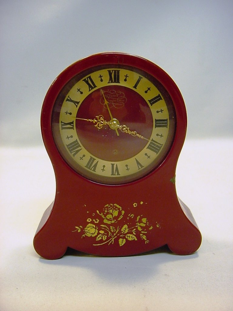 Early Swiss Jaeger Petite Teloise Music Clock: An early example of Jaeger music alarm clock. Red enamel with gilt rose decoration. Ste Croix, Switzerland. Measurements: 5" X 4" X 1.5"