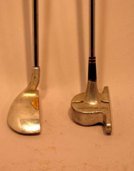 A Tom McNamara cast aluminium putter: A Tom McNamara cast aluminium putter, the shaped head with alignment aid, steel shaft; and an un-named aluminium head putter, boat shaped head with brass insert to face, steel shaft (2)