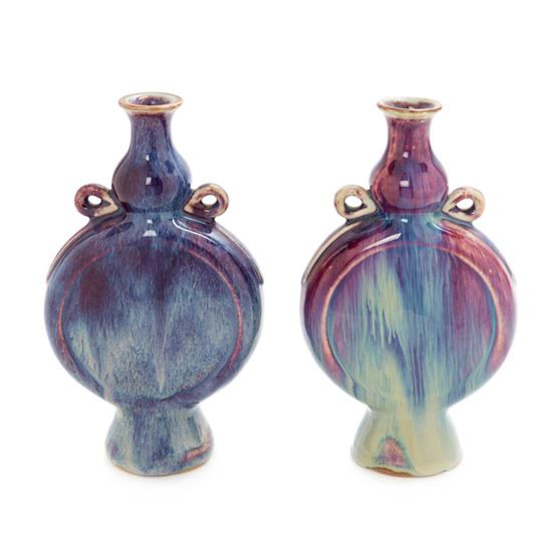 A Pair of Chinese Flambe Porcelain Flasks Height of: A Pair of Chinese Flambe Porcelain Flasks each having a flattened gour-form body resting atop a spreading foot, the shoulder set with a pair of loop handles. Height of each 9 inches. Estimate $300-500
